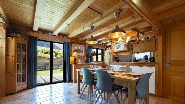 Un interior de madera con comedor, cocina y grandes puertas correderas de vidrio que dan a un patio exterior.