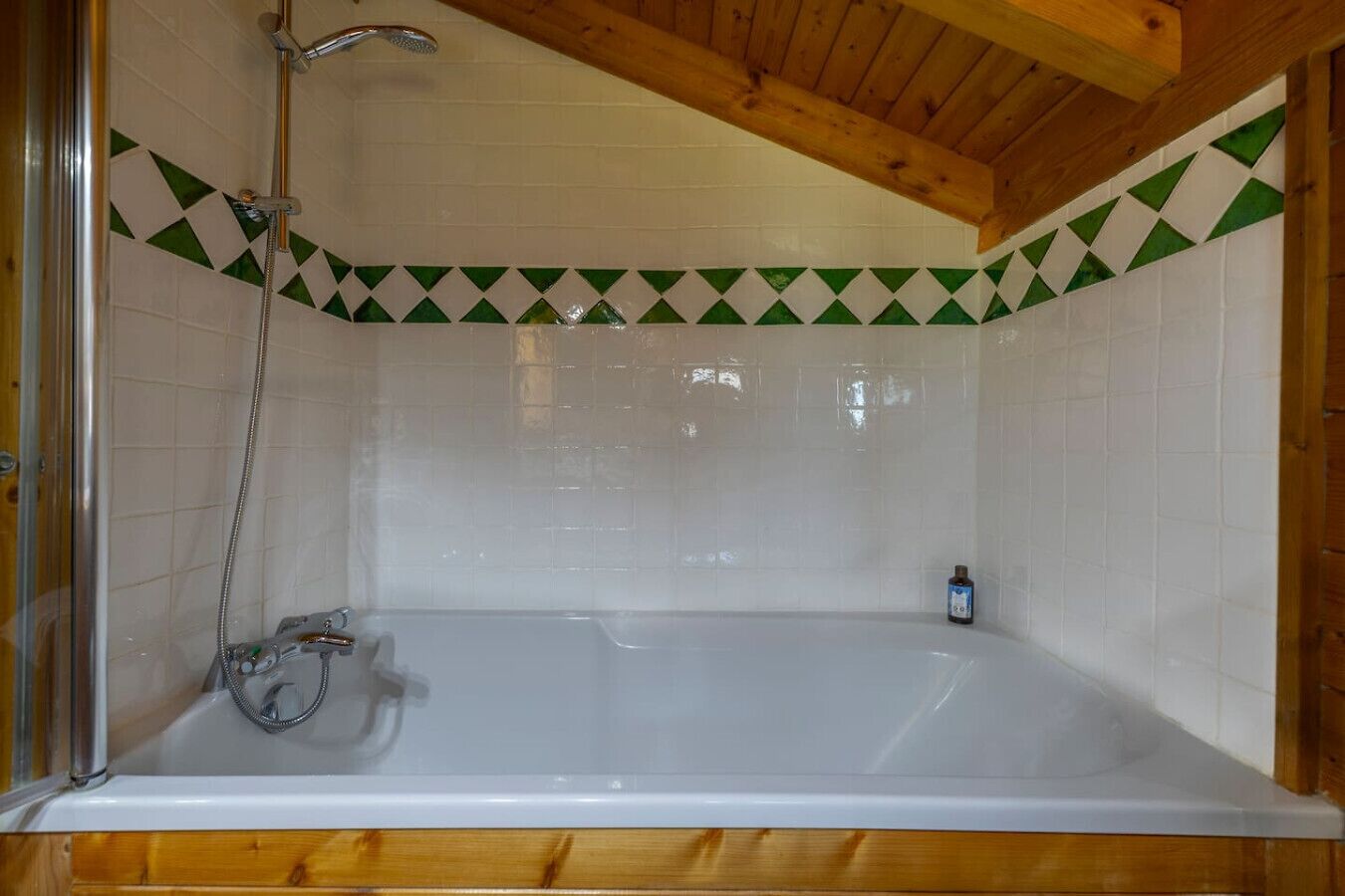 A bathroom with a bathtub, shower, and wooden ceiling.
