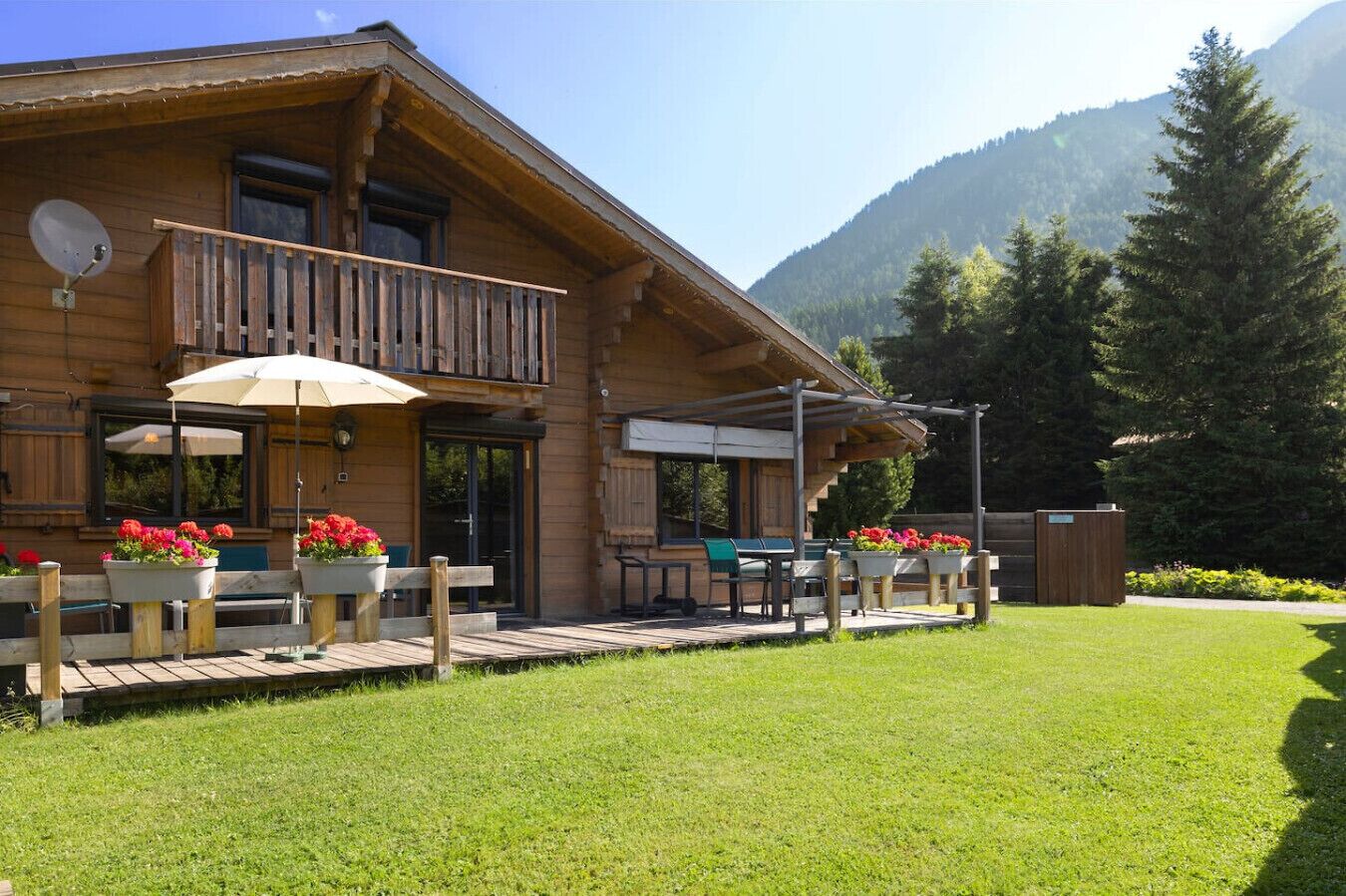 A wooden lodge with a balcony, outdoor seating, and flower planters.