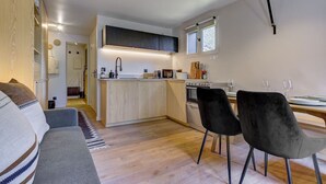 Una cocina moderna con una isla central, un comedor con dos sillas y un sofá en la sala.