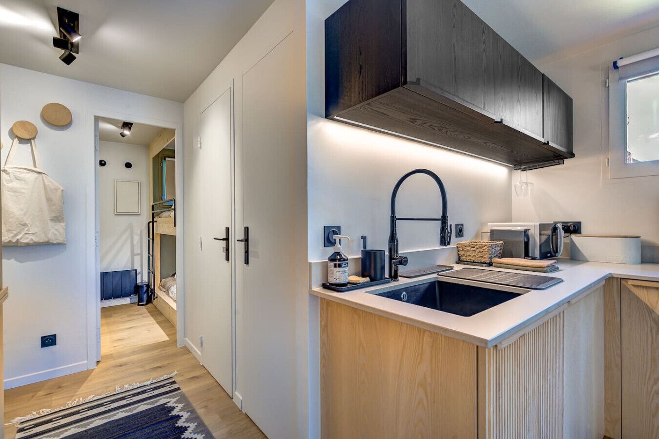 Une cuisine moderne dotée d’un évier encastré, de meubles en bois et d’un robinet noir.