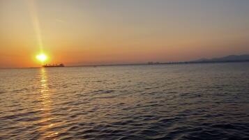 A calm body of water with a ship and distant land in the background.