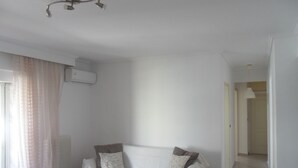 Sala de estar minimalista com sofá branco, mesa de centro de madeira e luminária no teto.