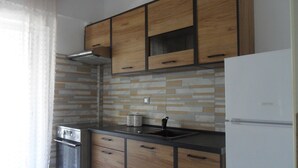 Cozinha com armários de madeira, forno de aço inoxidável e geladeira branca.