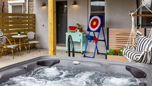 Un jacuzzi con terraza de madera, una hamaca y mobiliario exterior.