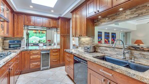A modern kitchen with wooden cabinets, granite countertops, a dishwasher, and a skylight. - Chic, Walkable Desert Retreat - Private & Serene (Palm Springs)