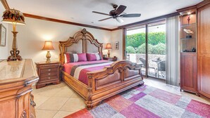 A bedroom with a large bed, a ceiling fan, a view through the glass door, and a wooden cabinet. - Chic, Walkable Desert Retreat - Private & Serene (Palm Springs)