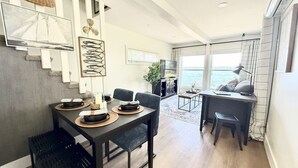 Un comedor moderno con una mesa preparada para cuatro personas, un sofá y vistas al mar.