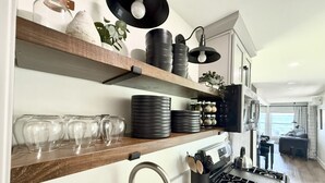 Una cocina moderna con estantes de madera, una estufa a gas y un fregadero.