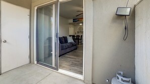 Eine Glastür öffnet sich zu einem Wohnbereich mit einem dunkelgrauen Sofa und einem Esstisch.