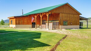 A wooden barn-style building with a green roof, a covered porch, and an American flag. - Studio Cabin w/ Mtn Views by the Green River! (Cora)