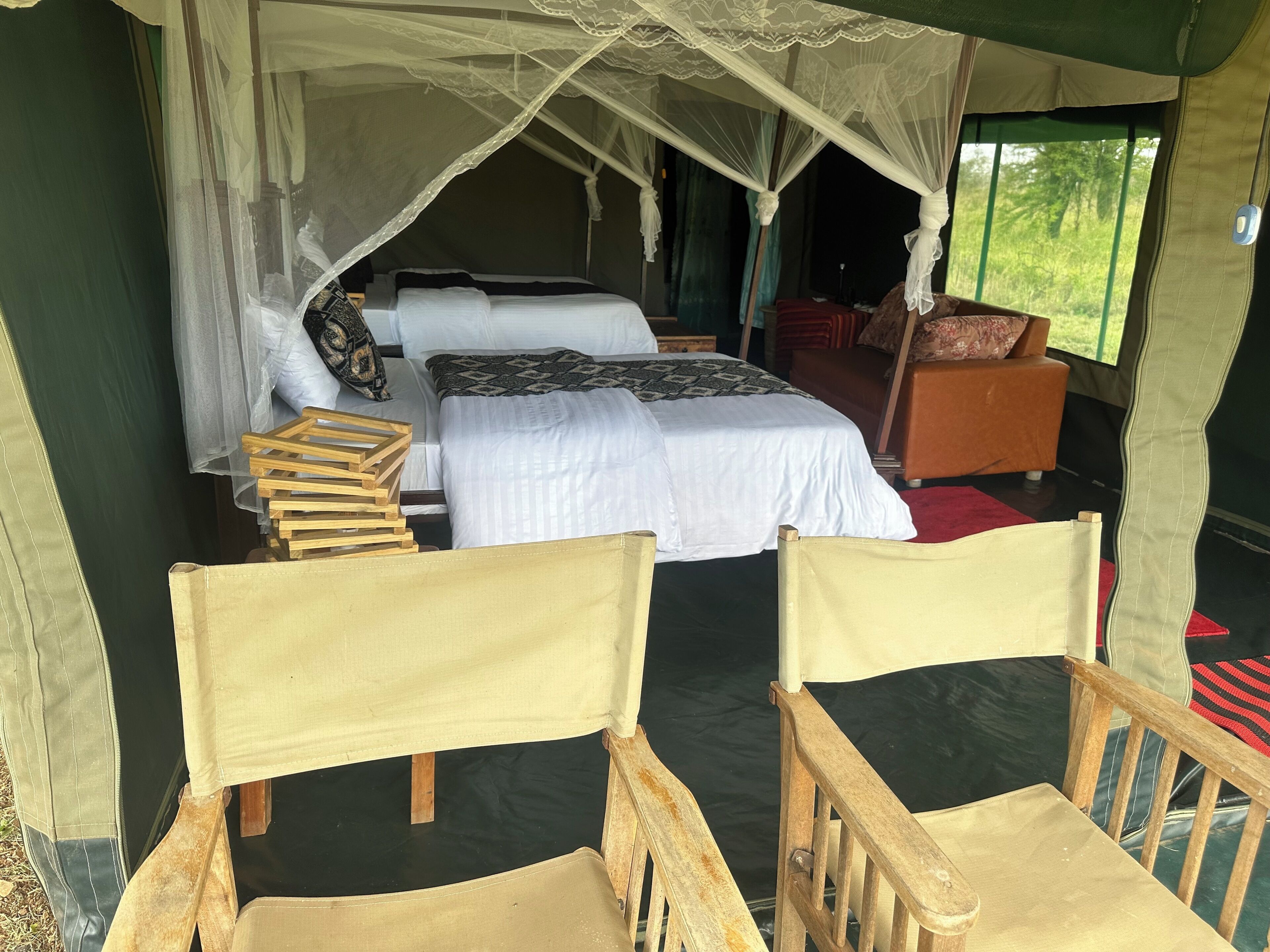 Alojamiento con tienda de campaña, una cama, una silla de madera y una mesa.