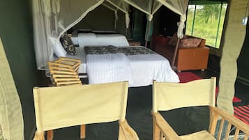 Alojamiento con tienda de campaña, una cama, una silla de madera y una mesa.