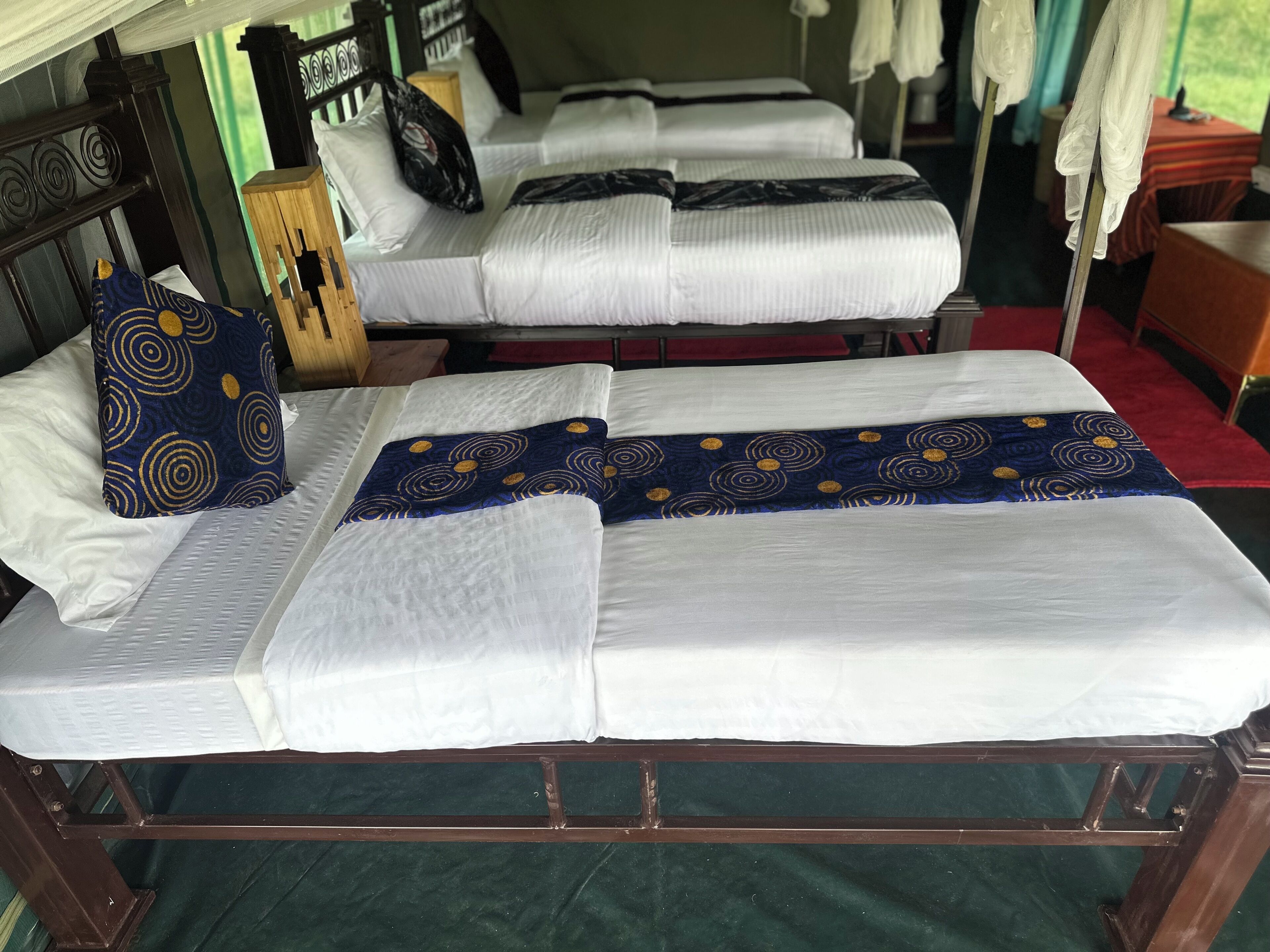 A room with two single beds, each with white bedding and a blue patterned pillow.