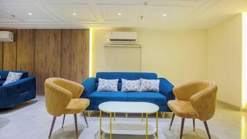 A modern living room with a blue sofa, two yellow armchairs, and a white coffee table.