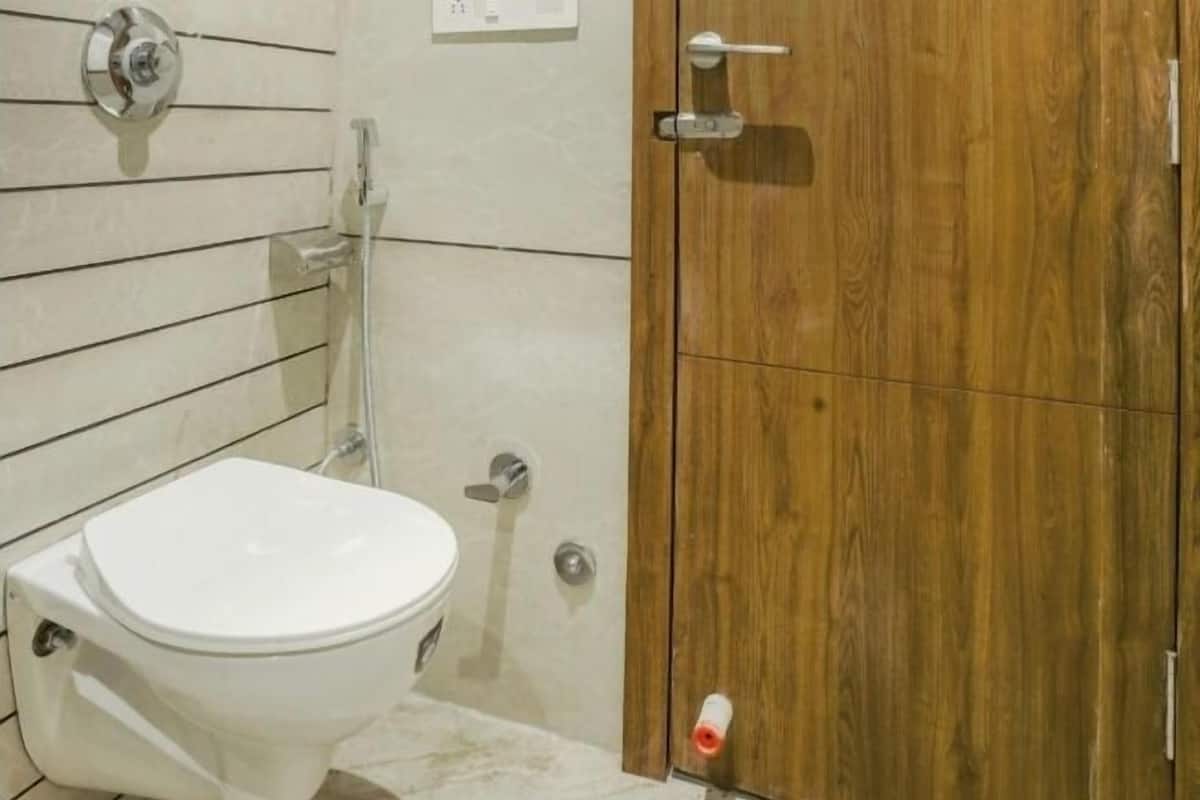 Un baño con inodoro blanco, puerta de madera y zona de ducha.