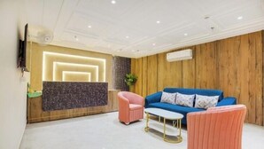 Una sala de estar moderna con un sofá azul, sillones rosados y una mesa de centro blanca.