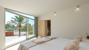 A modern hotel room with a large bed, a balcony with a palm tree, and a view of the outdoors. - La de Ros - Javea, Costa Blanca (Javea)