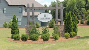 Letrero de Cyprus Cove Townhomes con una pérgola de madera y jardín ajardinado.