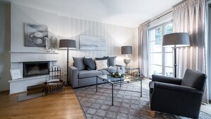 Ein modernes Wohnzimmer mit Sofa, Sessel, Couchtisch und Kamin.