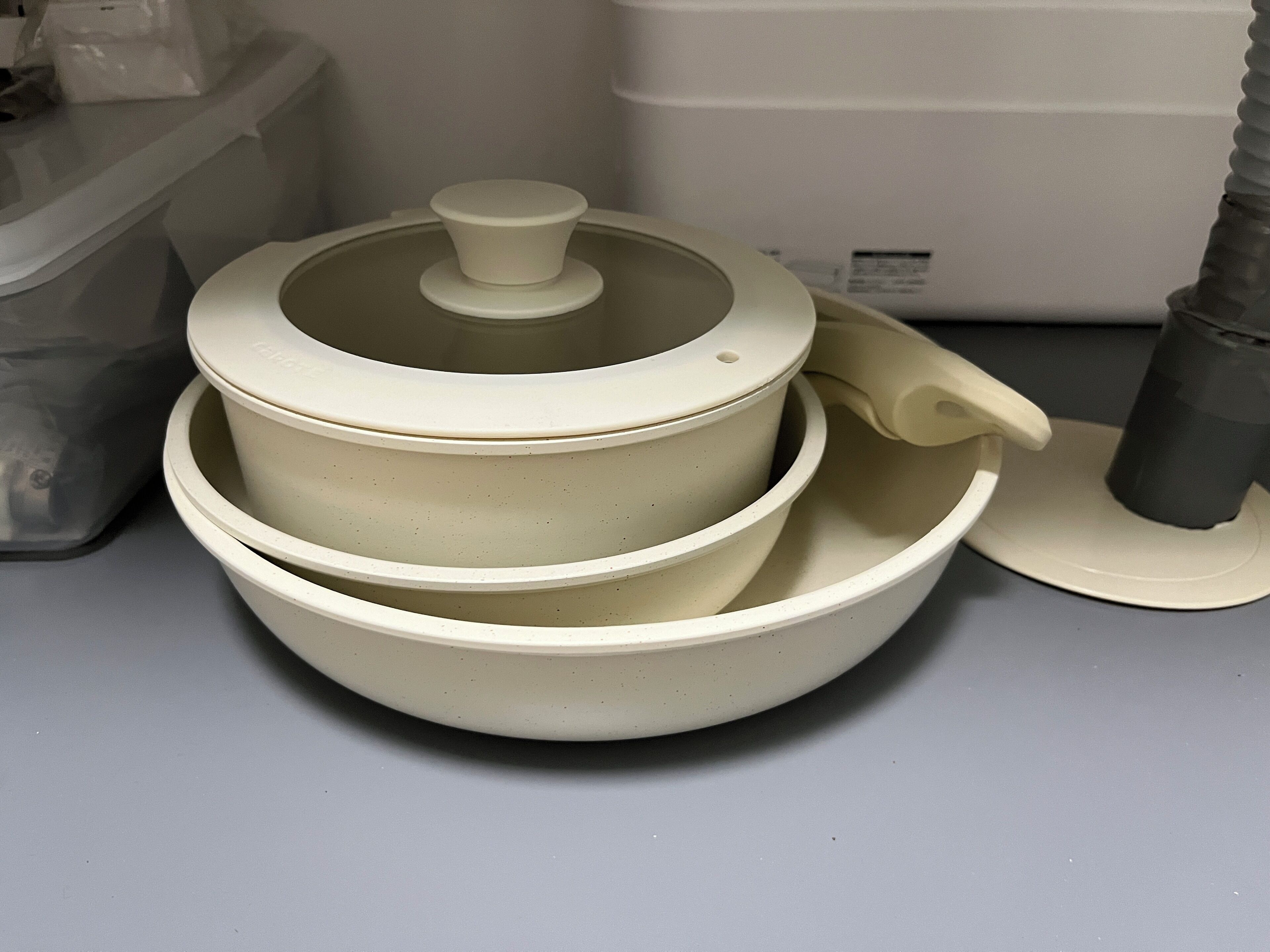 A set of stacked white bowls with lids, placed on a grey surface.