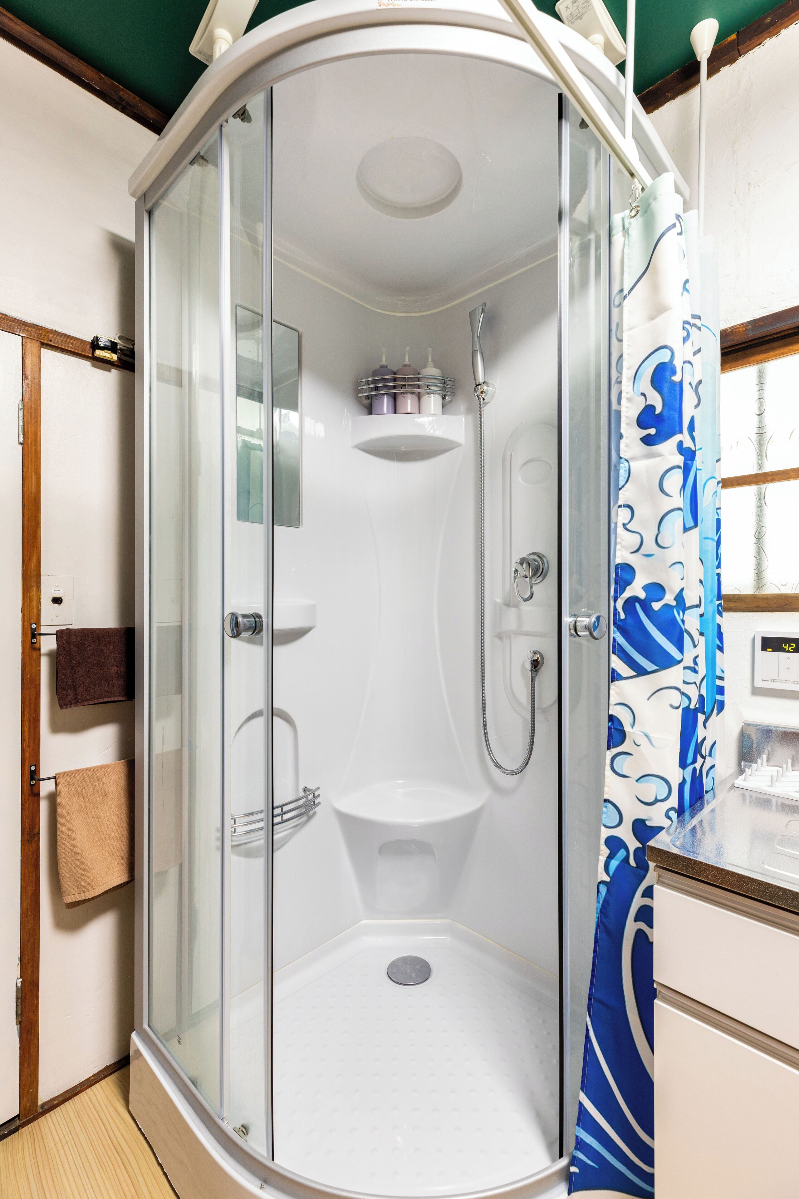 A glass-enclosed shower stall with a white sink and a towel rack.