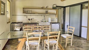 Una cocina con mesa, sillas, estufa, microondas y lavadora.