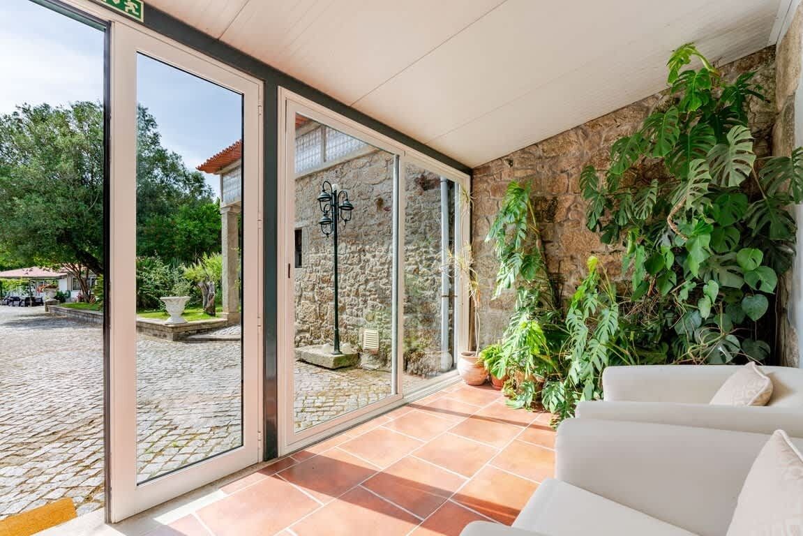 Un interior moderno con una pared de piedra, una puerta de cristal que da al exterior y un sofá blanco.
