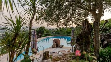 Una piscina rodeada de entorno natural, con árboles y rocas.