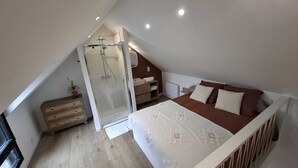 A bedroom with a sloped ceiling, a bed, a bedside table, a nightstand, a walk-in closet, and a shower. - Ty C&K Breizh (Plerguer)