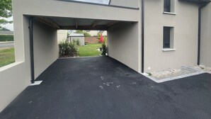 A modern house with a covered driveway and a small garden area. - Ty C&K Breizh (Plerguer)