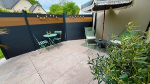 A patio with a table and chairs, a small umbrella, and a potted plant. - Ty C&K Breizh (Plerguer)
