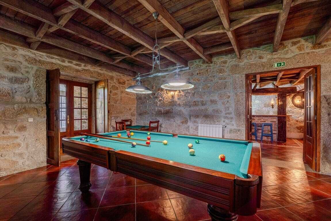 A pool table in a room with stone walls and wooden beams.