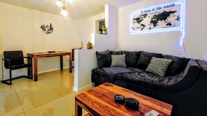 A modern living room with a dark grey sofa, a wooden coffee table, and a dining area with a wooden table and chairs. A world map is displayed on the wall. - Apartment "Liana" with view to the castle (Hechingen)