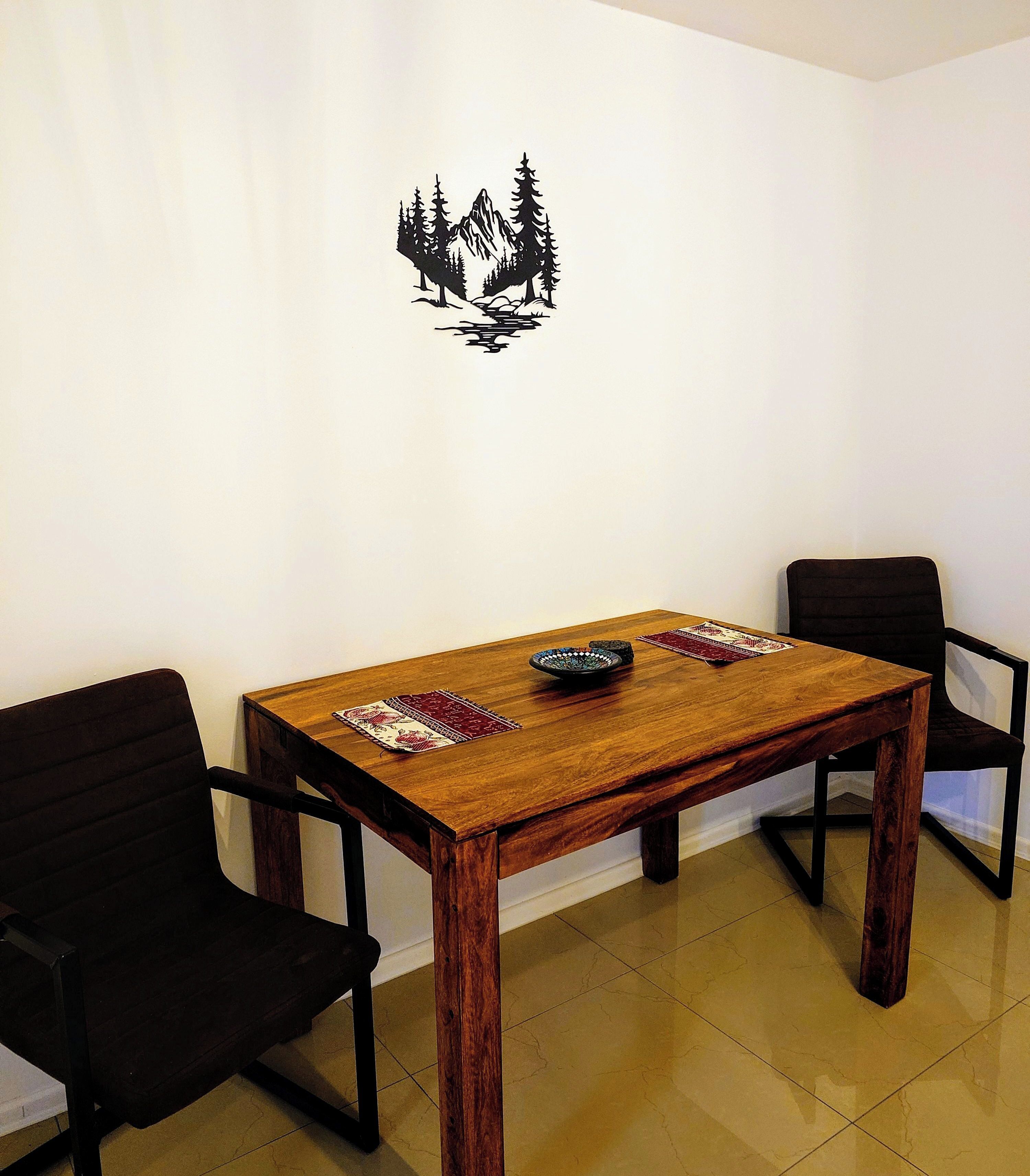 Un comedor con una mesa de madera, dos sillas y un adhesivo decorativo en la pared.