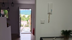 A hallway with a door leading to a balcony, a phone on the wall, and a small table with a plant. - Apartment "Liana" with view to the castle (Hechingen)