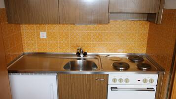 Een oven, een koffiezetapparaat/waterkoker, kookgerei, borden en bestek