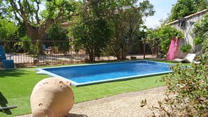 A rectangular swimming pool with a blue interior, surrounded by a fenced area with artificial grass. - Comfortable country house with swimming pool (Saint-Rémy-de-Provence)