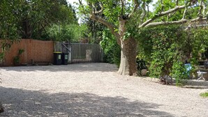 A gravel yard with a fenced area, trees, and a small building. - Comfortable country house with swimming pool (Saint-Rémy-de-Provence)