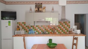 A compact kitchen with a tiled backsplash, a refrigerator, a coffee maker, and a green bowl on the table. - Comfortable country house with swimming pool (Saint-Rémy-de-Provence)