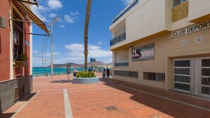 Un chemin piétonnier pavé de briques, avec un palmier et un bâtiment portant l’inscription « CLUB DEPORTIVO FRANCO ».