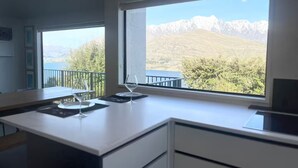 A modern kitchen with a large window offering a view of mountains and trees.