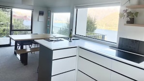 A modern kitchen with a large window, a dining area, and a balcony.