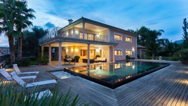 Une maison à deux étages dotée d’une piscine, d’une terrasse en bois et d’un espace salon extérieur.