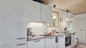 Une cuisine moderne avec des armoires grises, un four encastré et un plafond en bois.
