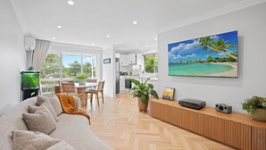 Una sala de estar moderna con un sofá grande, un comedor y una cocina al fondo.