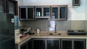 A compact kitchen with a built-in stove, a sink, and cabinets with glass doors. - Dharma Suweta (Ubud)
