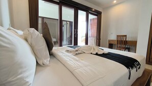A hotel room with a large bed, a desk, and a chair. - Dharma Suweta (Ubud)
