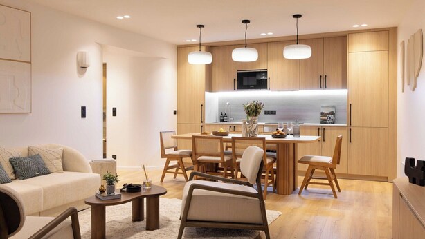Una cocina moderna con armarios de madera, un comedor con mesa y sillas, y una sala de estar con sofá y mesa de centro.