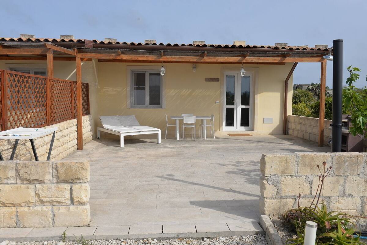 Un espace extérieur abrité comprenant un fauteuil, une table et des chaises.